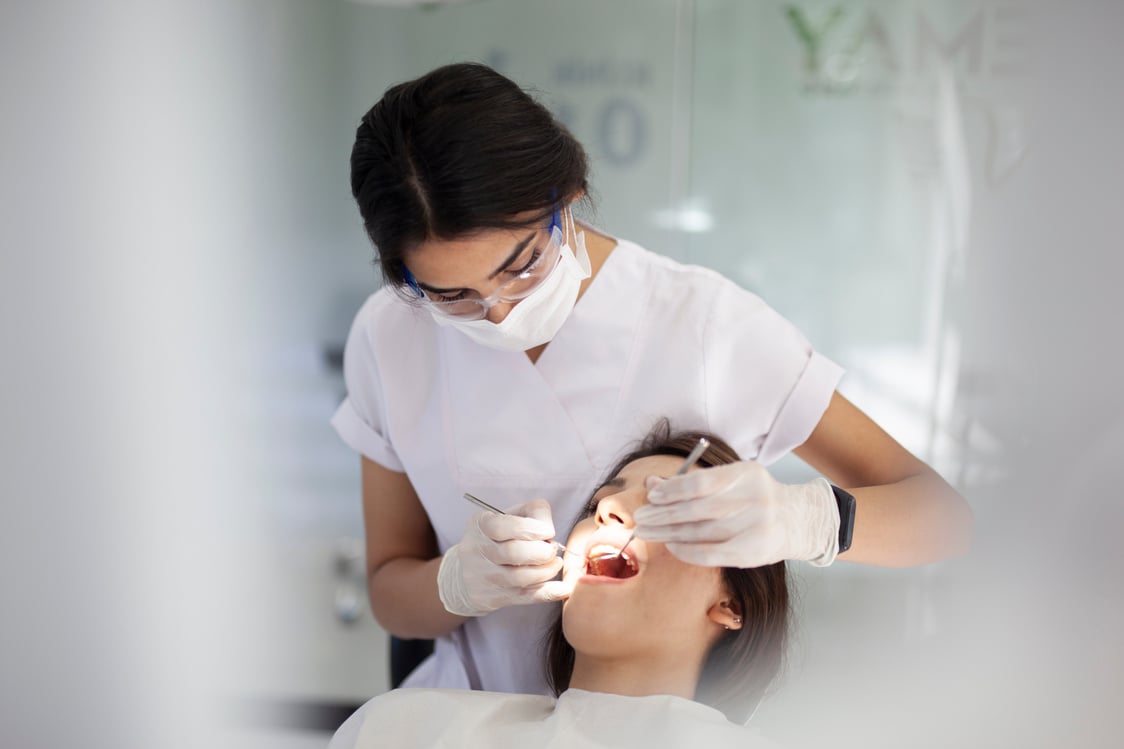 dental hygienist working on young woman's teeth