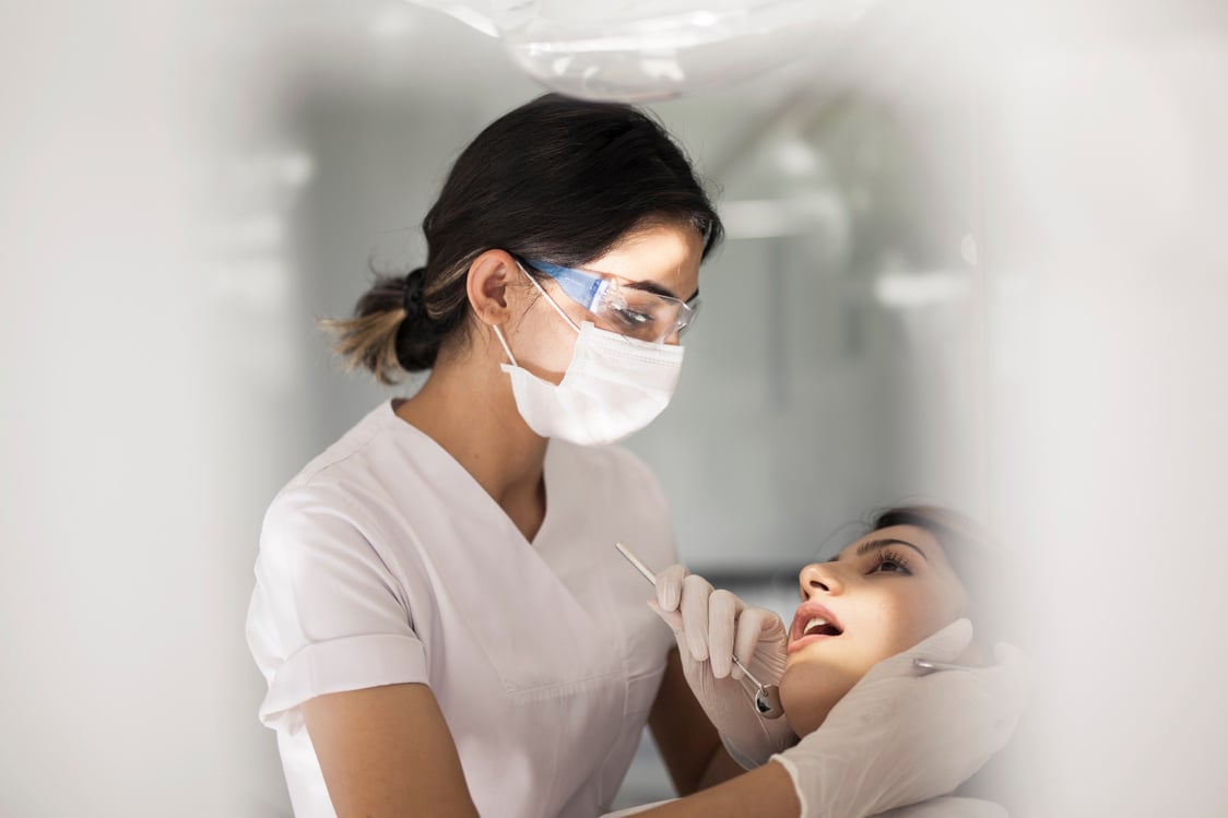 dental hygienist working on young woman's teeth